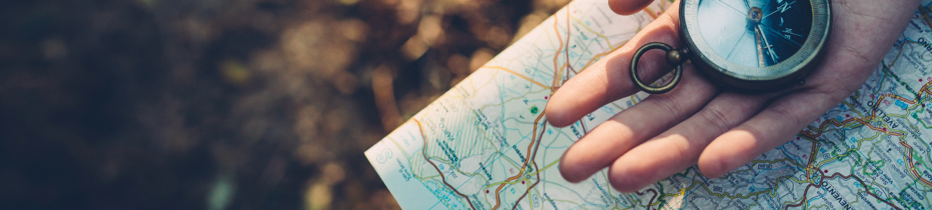 hand on map holding a compass